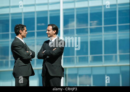 Business executives standing in front of office building talking Stock Photo