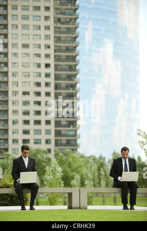 Businessmen using laptop computers outdoors Stock Photo