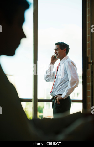 Silhouette of businessman using cell phone by window Stock Photo