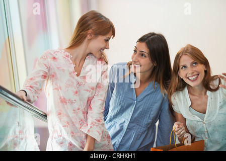 Smiling young women standing on escalator Stock Photo