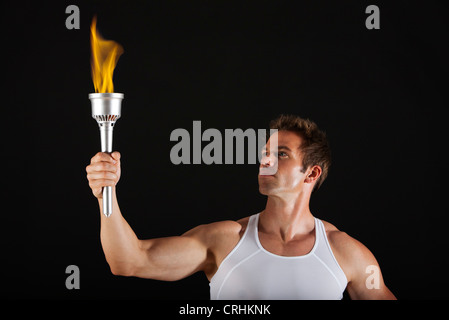 Male athlete holding up torch Stock Photo