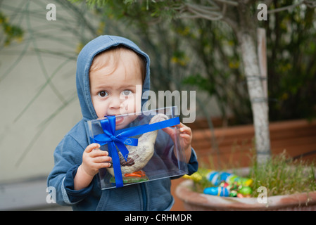 Toddler boy biting box containing Easter candy Stock Photo