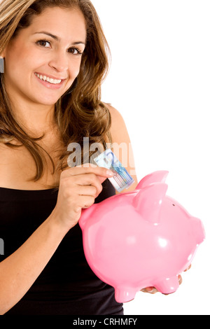 beautiful young woman putting some money for her savings in a pink piggybank Stock Photo