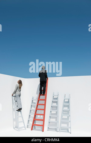 Businessman and businesswoman climbing ladders Stock Photo