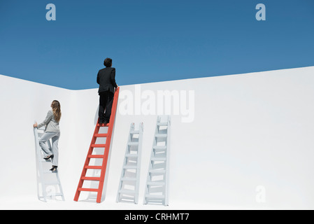 Businessman and businesswoman climbing ladders Stock Photo