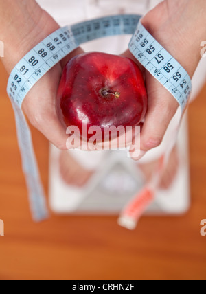 Woman on a scale with an apple and a measuring tape Stock Photo
