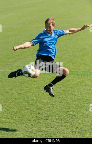 Soccer player kicking ball in midair Stock Photo