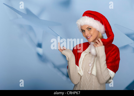 Woman wearing Santa hat in front of festive background, portrait Stock Photo