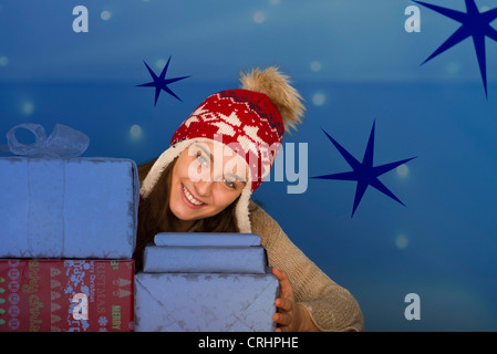 Young woman behind stacked Christmas presents, portrait Stock Photo