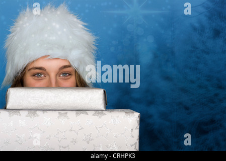 Young woman peeking over stack of Christmas gifts, portrait Stock Photo