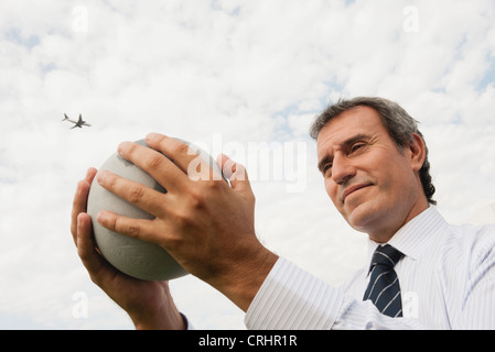 Mature man holding stone globe Stock Photo