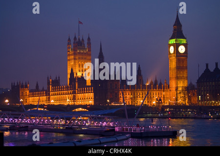 Houses of Parliament, Big Ben, London Eye Pier & Westminster Bridge floodlit at night, seen over  River Thames from South Bank Stock Photo