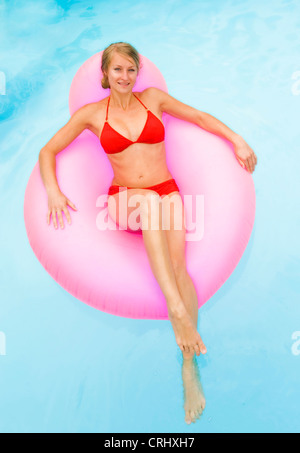 young attractive woman on airbed in swimming pool Stock Photo