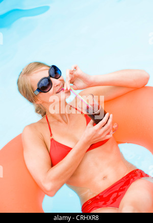 young attractive woman on airbed in swimming pool Stock Photo