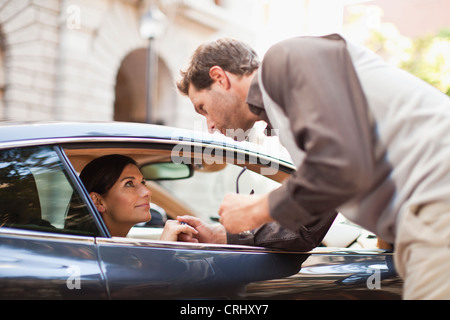 Man talking to woman through car window Stock Photo