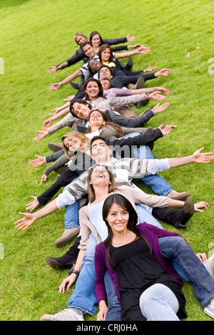 happy group of friends in in a park sitting behind each other Stock Photo