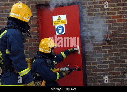fire fighters opening a door to put out the fire Stock Photo