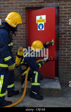 fire fighters opening a door to put out the fire Stock Photo