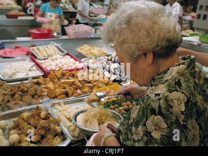 Older woman fills up a plate of small fish Stock Photo