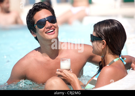 casual couple with sunglasses and drinks, relaxing at the jacuzzi Stock Photo
