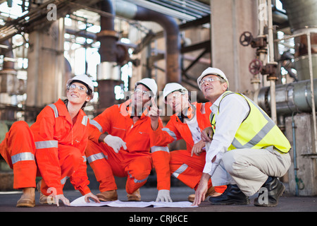 Workers with blueprints at oil refinery Stock Photo