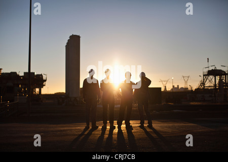 Silhouette of workers at oil refinery Stock Photo