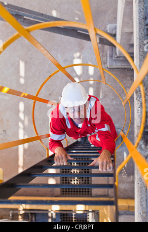 Worker climbing ladder at oil refinery Stock Photo