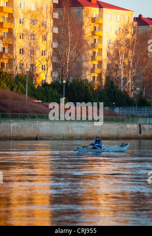 Isolated caucasian male trolling from a rowboat / skiff / dinghy at river Oulujoki at the center of the city of Oulu , Finland Stock Photo