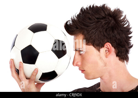 young soccer player holding a ball in front of his face and eying it Stock Photo