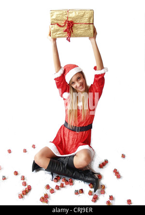 young blonde woman in Santa Claus dress holding gift into the air with a smile Stock Photo