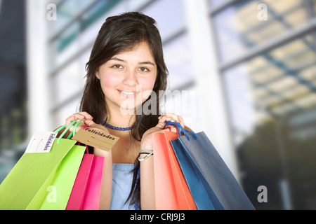 young girl in front of shopping centre holding up shopping bags with a smile Stock Photo