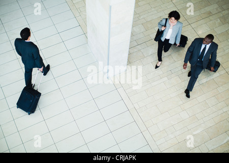 Business people rolling luggage in lobby Stock Photo