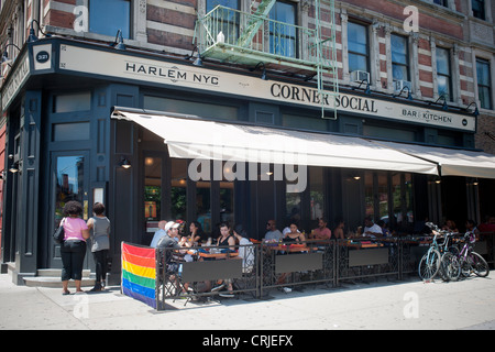 Patrons sit at the outdoor cafe of The Corner Social restaurant on Lenox Avenue in the neighborhood of Harlem in New York Stock Photo