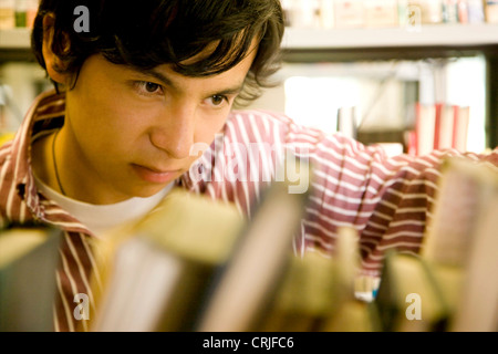 male university student at the library looking for a book Stock Photo