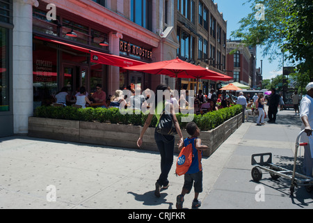 Patrons sit at the outdoor cafe of the Red Rooster restaurant on Lenox Avenue in the neighborhood of Harlem in New York Stock Photo