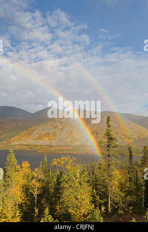 A rainbow arcs over autumn colors and Grayling Lake along the James Dalton Highway in the southern Brooks Range Mountains Stock Photo