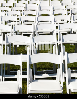 Rows of formal white wooden wedding chairs set up for a wedding or concert Stock Photo