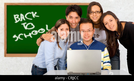 Casual group of students smiling in a classroom with a blackboard in the background with the words back to school Stock Photo
