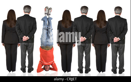 row of business people turning their backs to the camera except for a young man in casual clothing doing a headstand Stock Photo