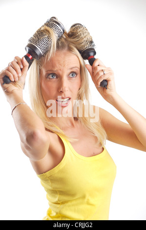 blond young woman using two hairbrushes as curlers Stock Photo