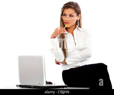 business woman looking pensive while sitting on her desk with a laptop Stock Photo