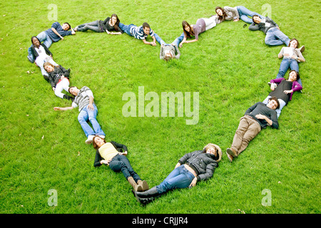 happy group of friends making a heart shape - smiling outdoors in a park Stock Photo
