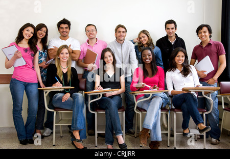 friends or university students smiling in a classroom Stock Photo