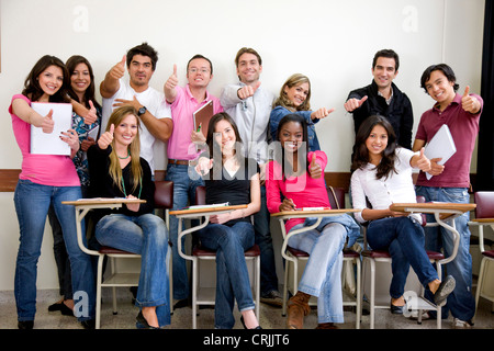 friends or university students smiling in a classroom wuth thumb up Stock Photo