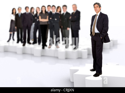 business leadership and teamwork with a businessman in front of a businessteam all standing on puzzle pieces Stock Photo