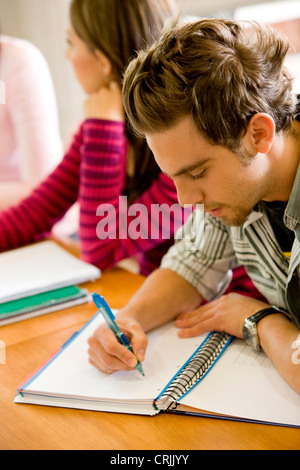 young man studying in the classroom writting on his notebook Stock Photo