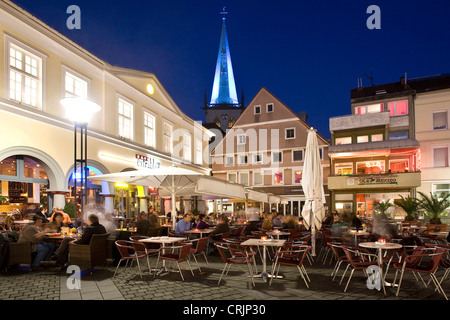 people siiting in a street restaurant on market place of Unna at blue hour, the illuminated tower church, Stadtkirche, in the background, Germany, North Rhine-Westphalia, Ruhr Area, Unna Stock Photo