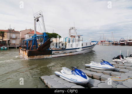 fishing trawler passing the chanal in Le Grau-du-Roi, with Jet Skis in the foreground, France, Languedoc-Roussillon, Camargue, Le Grau-du-Roi Stock Photo