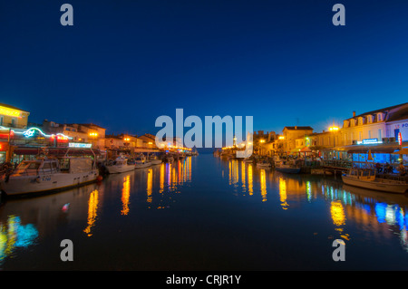 the chanal in Le Grau-du-Roi at twilight, with fishing boats and restaurants on both sides of the chanal, France, Languedoc-Roussillon, Camargue, Le Grau-du-Roi Stock Photo