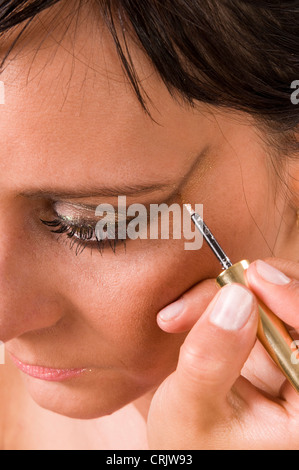 brunette young woman having an eye-catching eye-make-up put on by a cosmetician Stock Photo